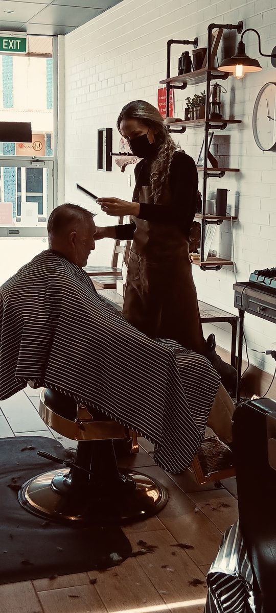 Barber giving a client a haircut in the shop