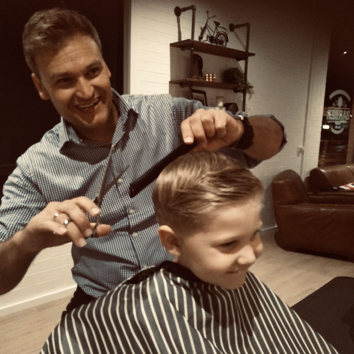Barber giving a young boy a haircut, smiling